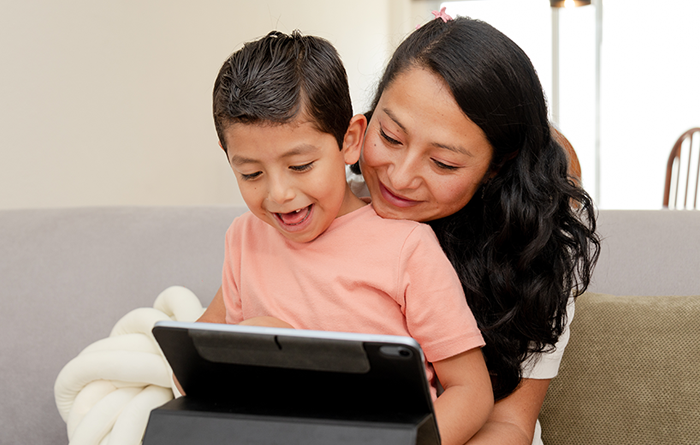 Mother reading to her son while he sits on her lap.